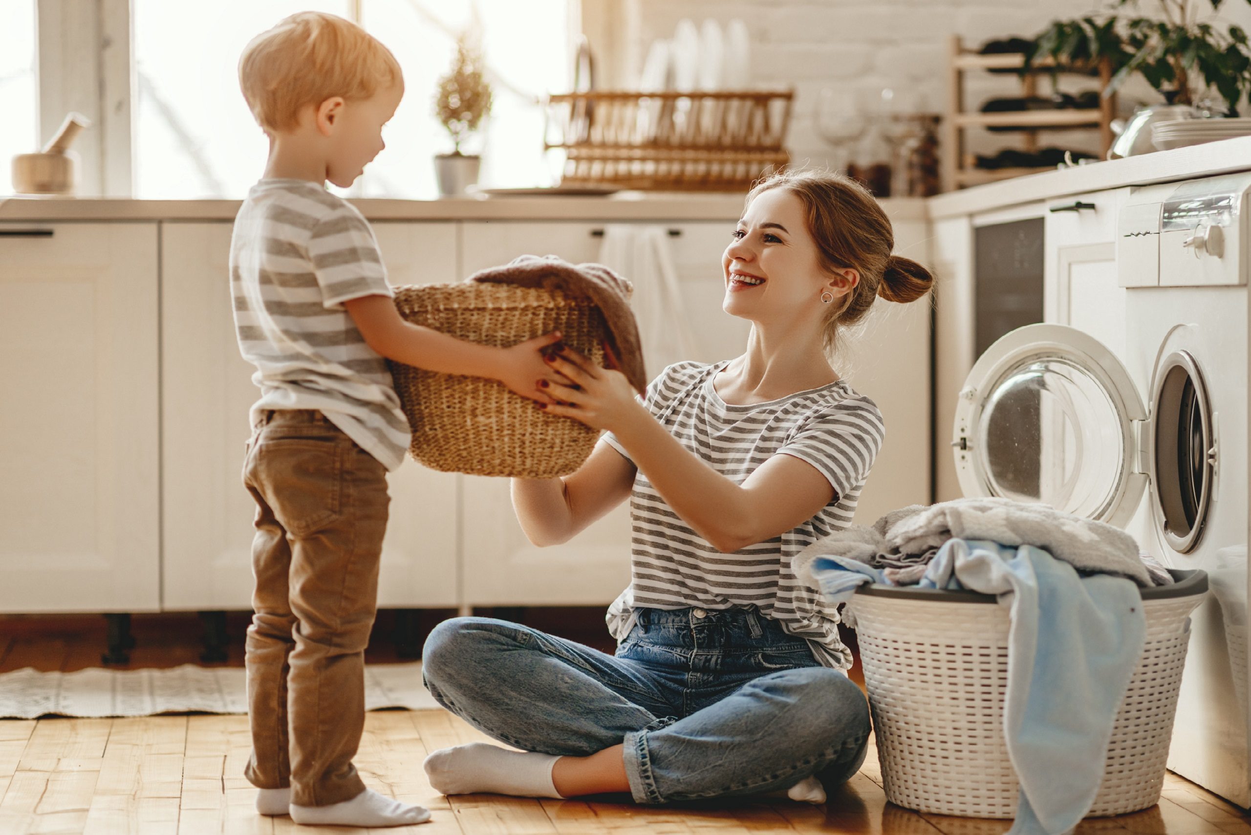 happy family mother housewife and child   in laundry with washing machine